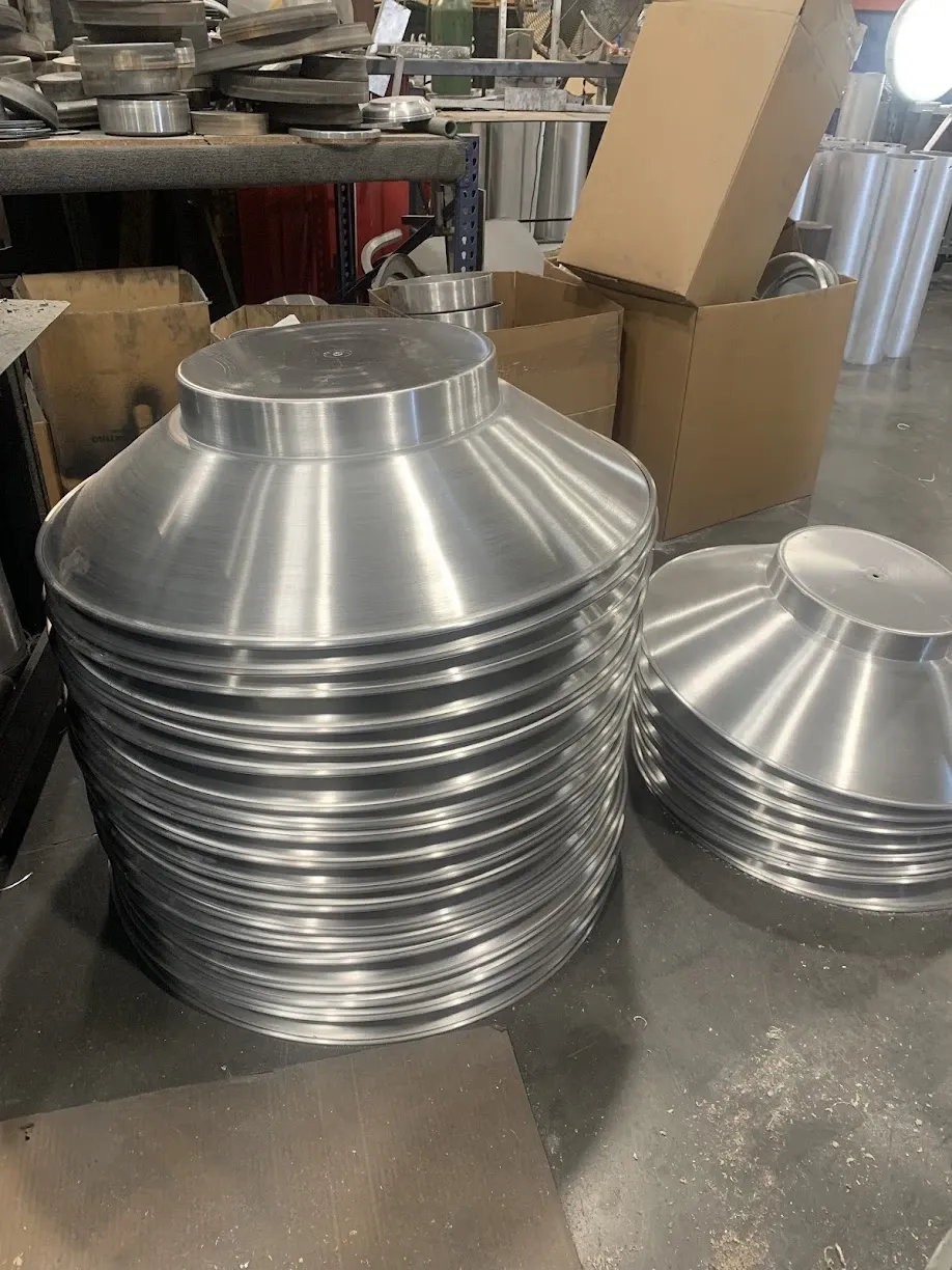 Two stacks of spun aluminum shades on the shop floor